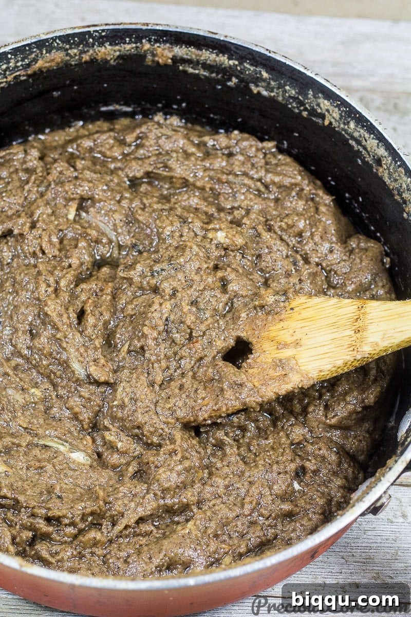 Wooden spatula stirring Cameroonian mboh in a pot.