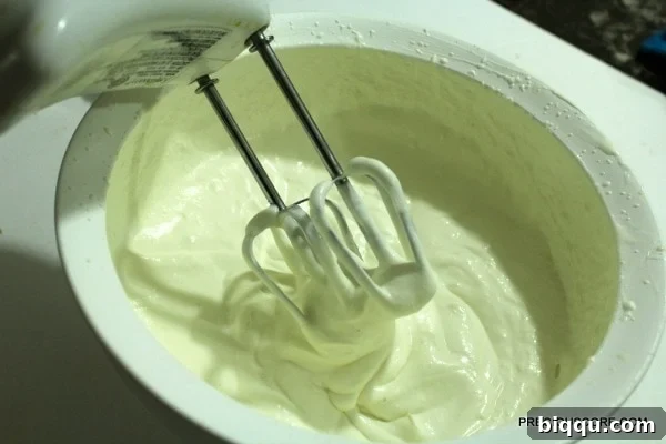 Whipped heavy cream and sweetened condensed milk forming soft peaks