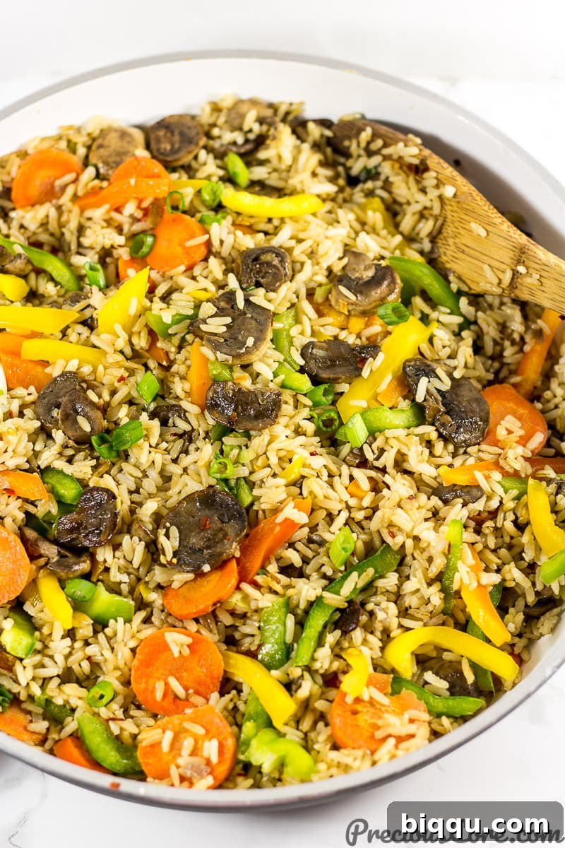 A pan of sizzling mushroom fried rice, rich with vegetables.