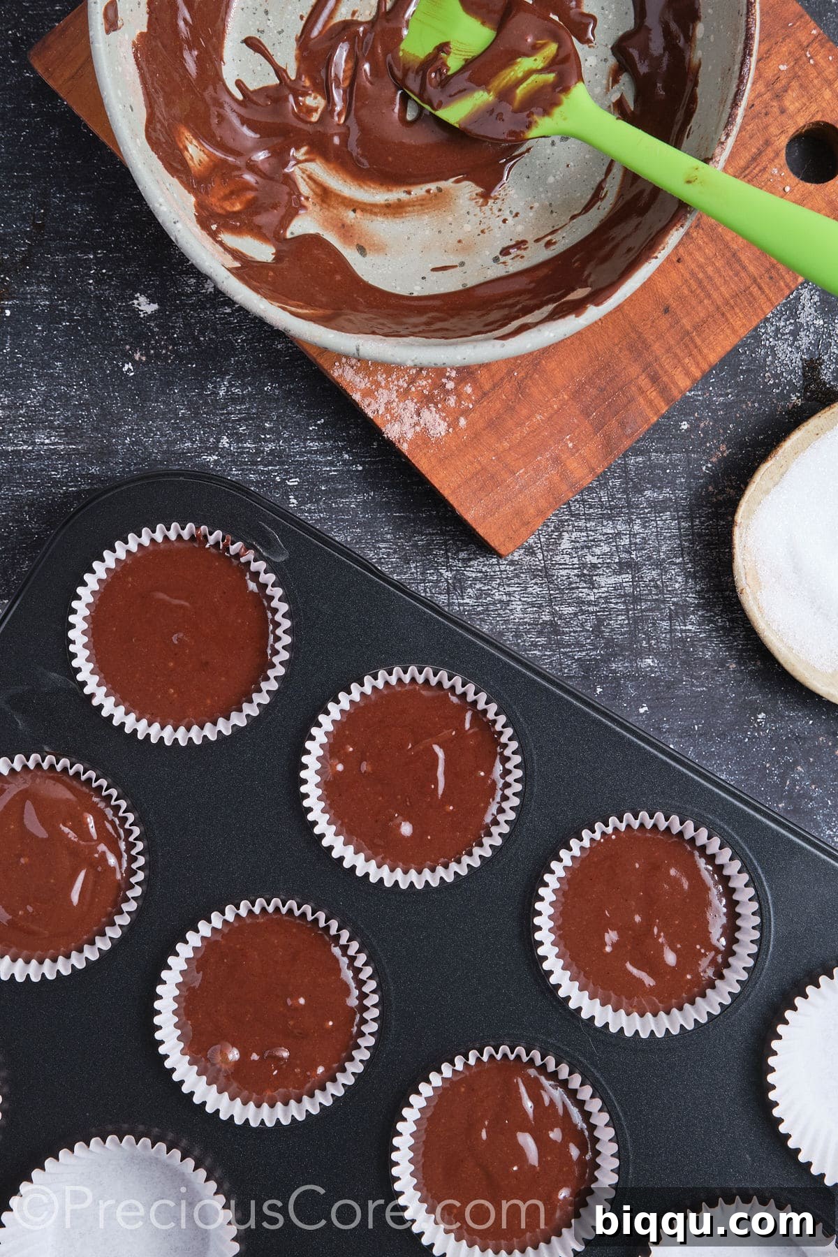 Chocolate cupcake batter in a muffin pan, ready for baking.