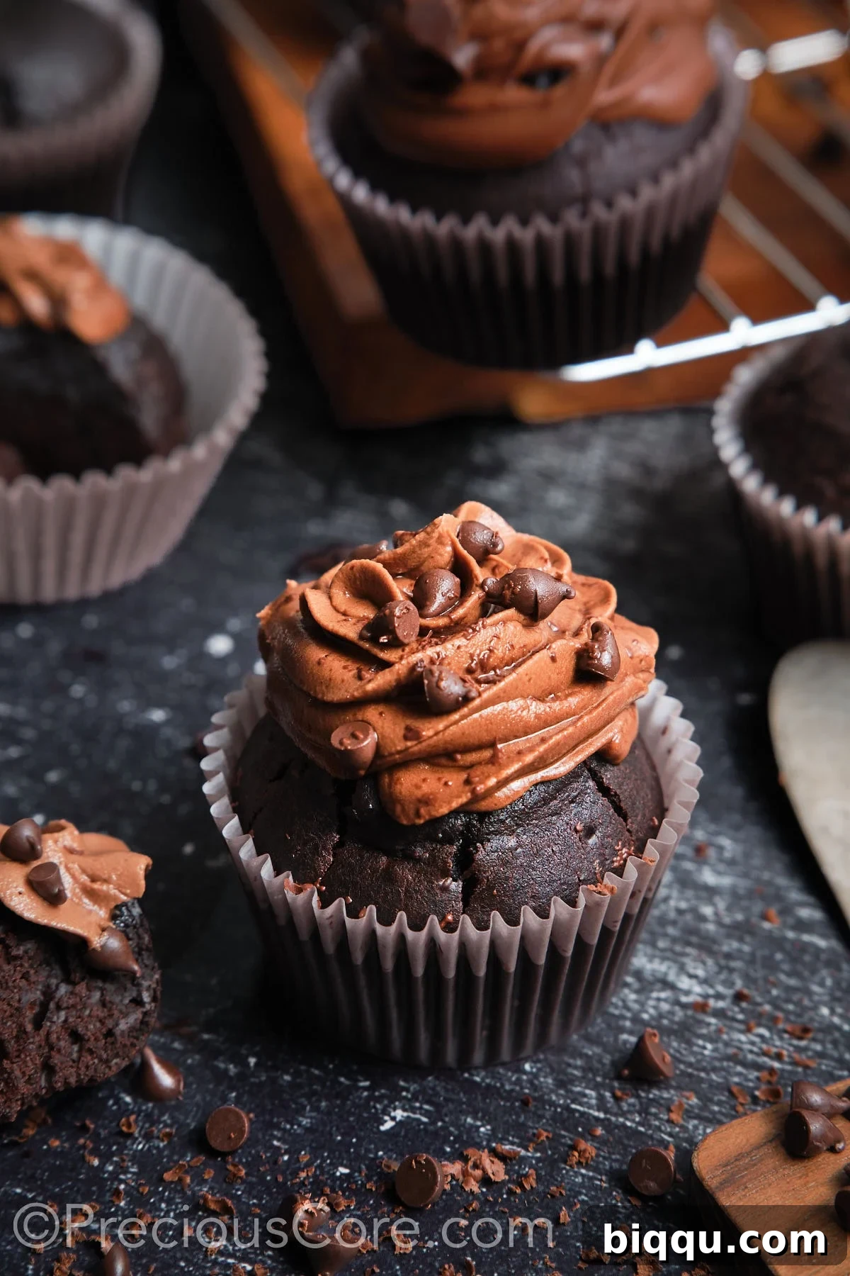 A beautifully frosted chocolate cupcake, garnished with chocolate chips, ready to be enjoyed.