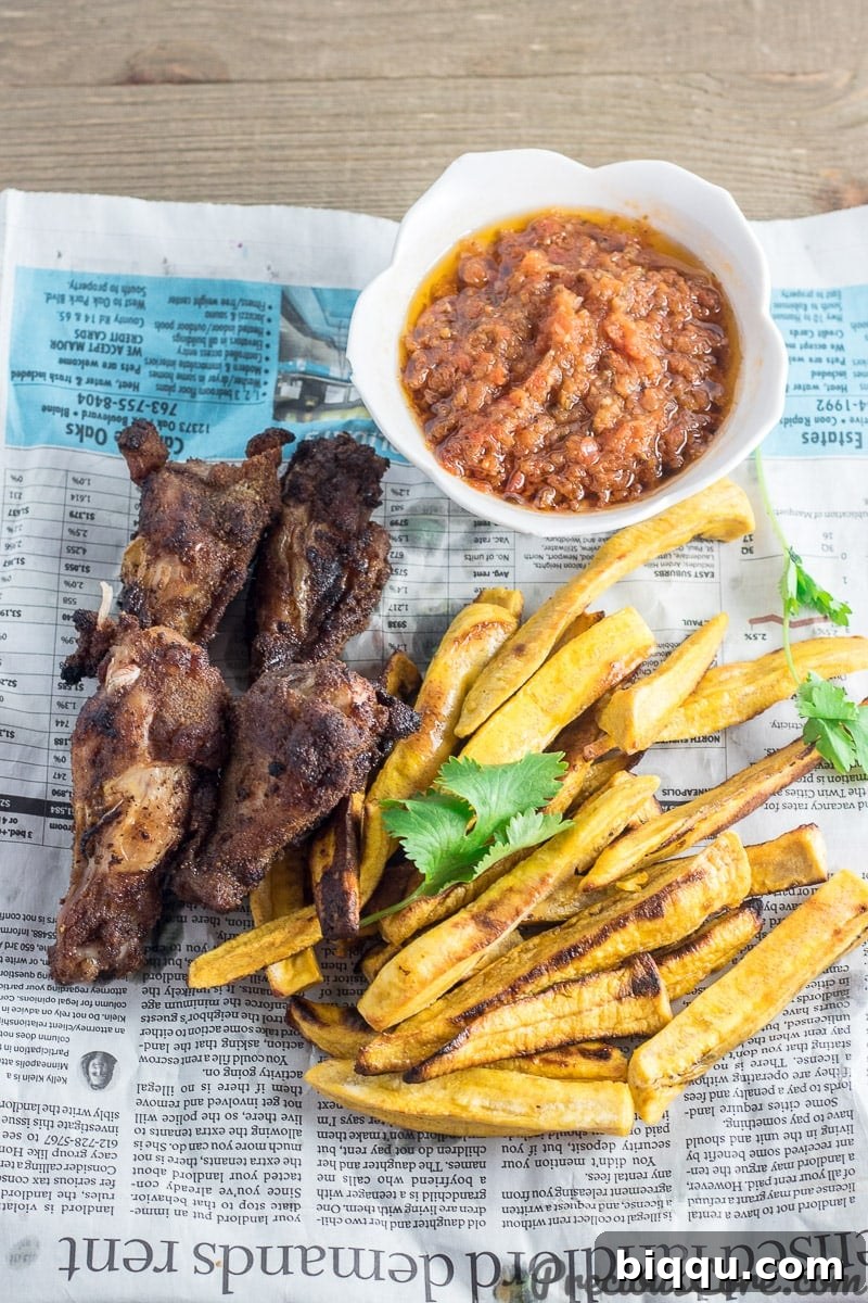 A delicious plate featuring perfectly baked plantain fries, seasoned chicken wings, and fresh greens, ideal for a hearty meal.