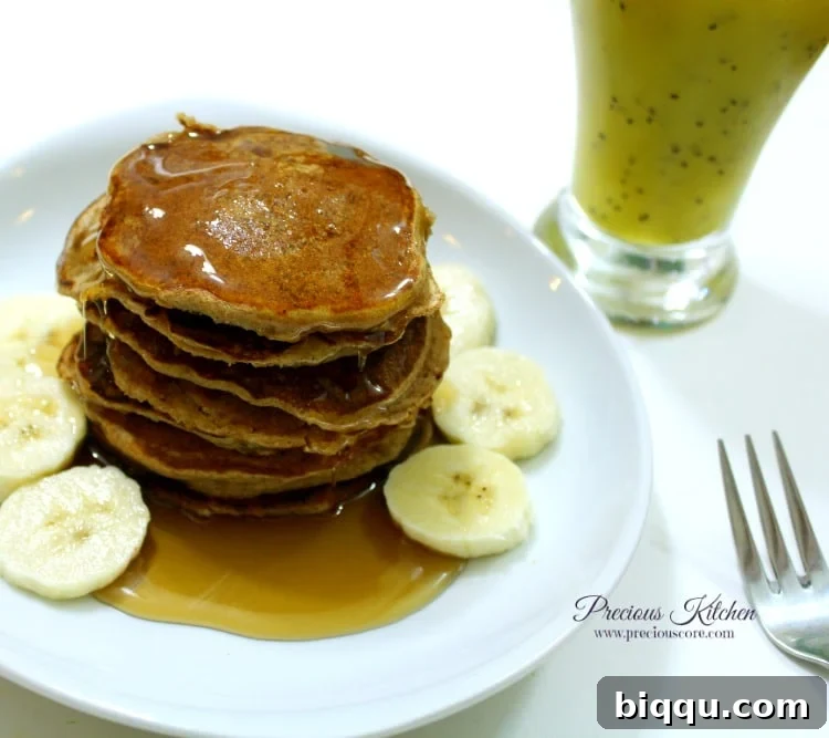 Stack of whole wheat banana pancakes drizzled with honey, served with fruit