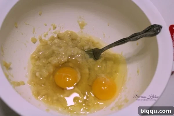 Adding eggs to mashed bananas in a bowl