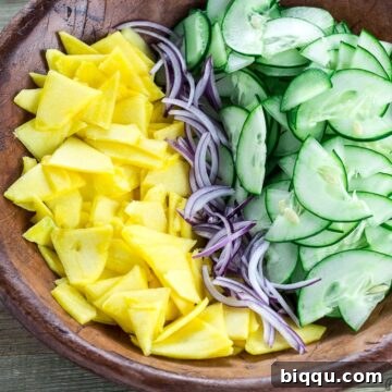 Refreshing Cucumber Mango Salad 7 Sliced cucumber, mango and onion in a bowl, ready for dressing