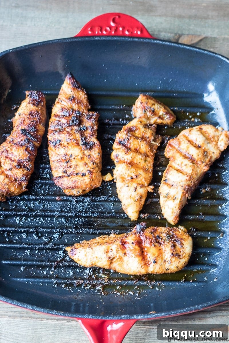 Grilled chicken tenders cooking in a cast iron grill pan on the stovetop