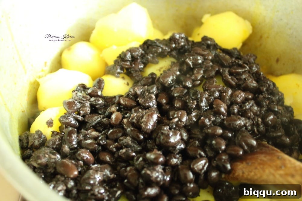 Boiled potatoes and beans added to the palm oil and spice mixture