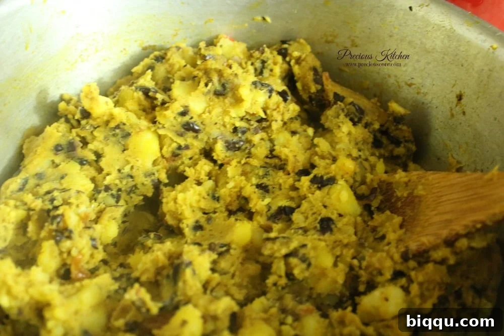 Mashing potatoes and beans with a wooden spoon in the pot
