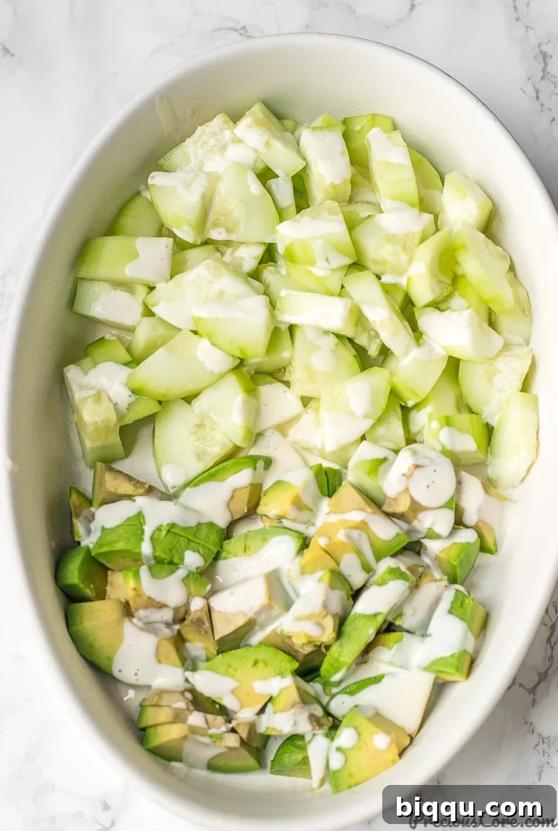 Cucumber Avocado Salad in a bowl with Mayonnaise Dressing drizzled on top