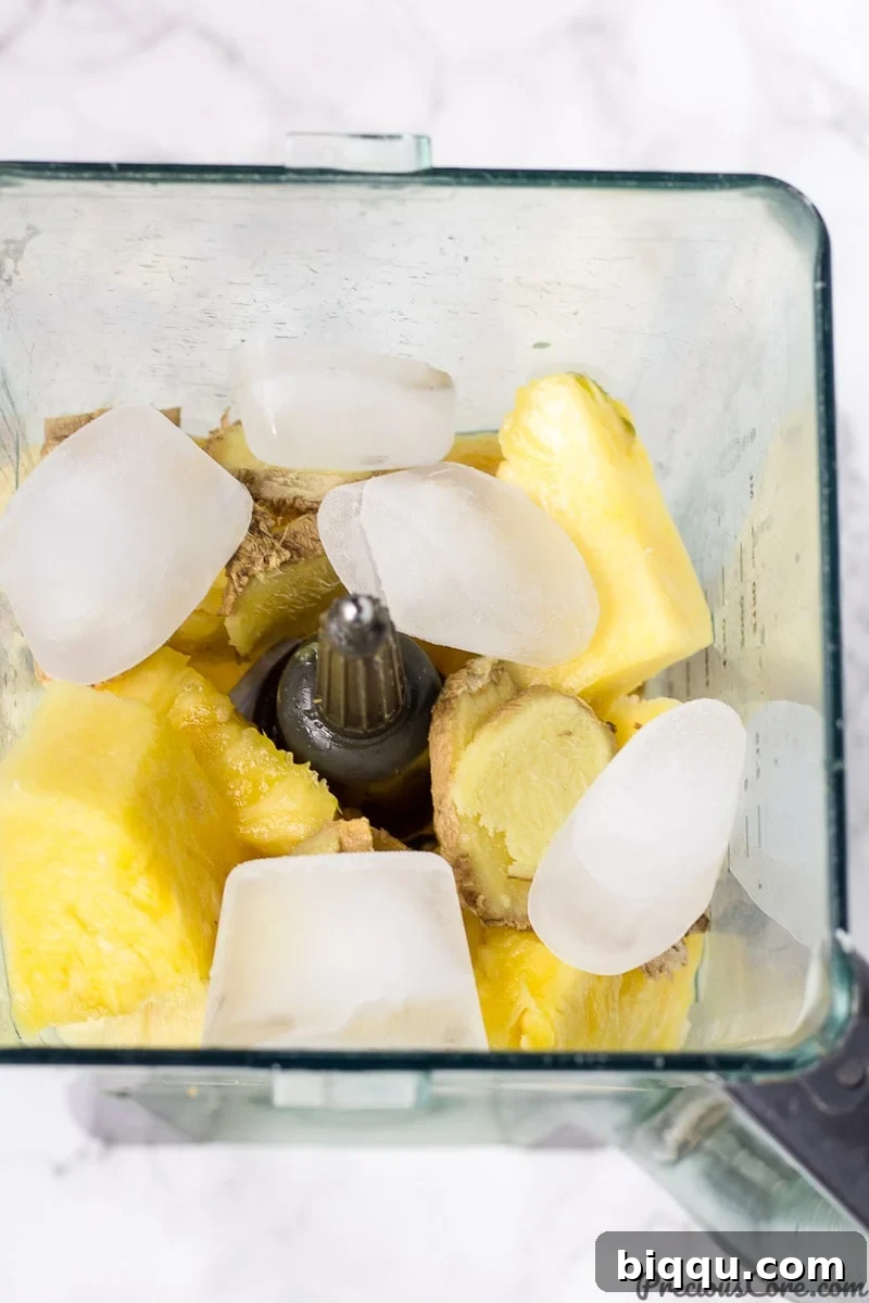 Tropical Ginger Kick 4 Fresh pineapple chunks, ginger root, and lemon slices in a blender, ready to be processed into juice.