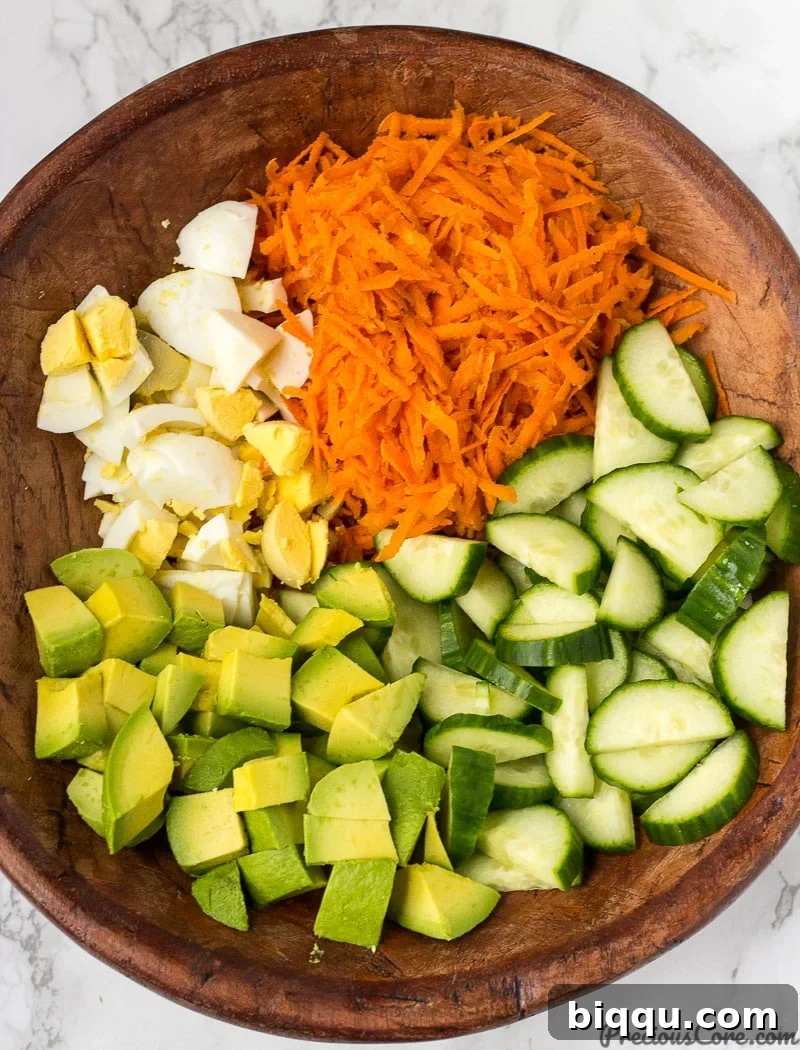 Chopped ingredients in a bowl for Breakfast Salad: carrots, cucumber, avocado, and eggs