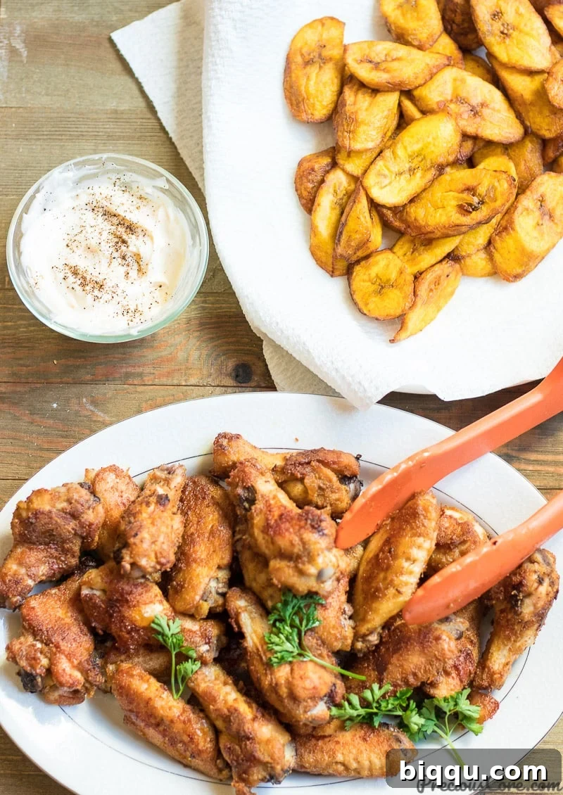 Oven grilled chicken wings served with sweet fried plantains and herby mayo, highlighting their crispy texture and delicious golden-brown finish.