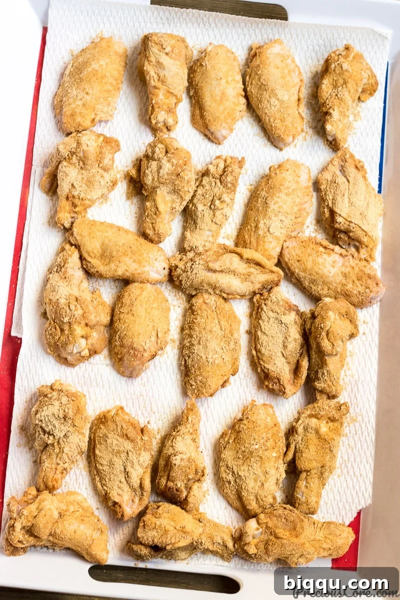 Party wings generously coated with a rich, dry spice rub, ready for the oven, displaying the vibrant colors of the suya seasoning.