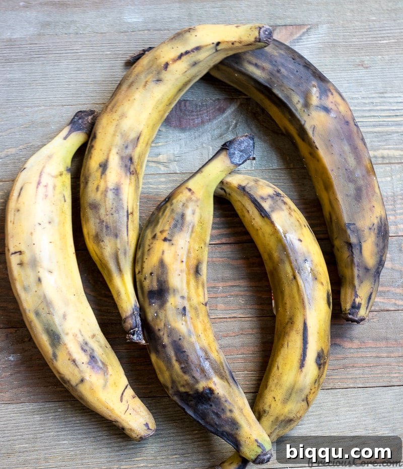 Five ripe yellow plantains arranged on a rustic wooden board, ready for preparation.