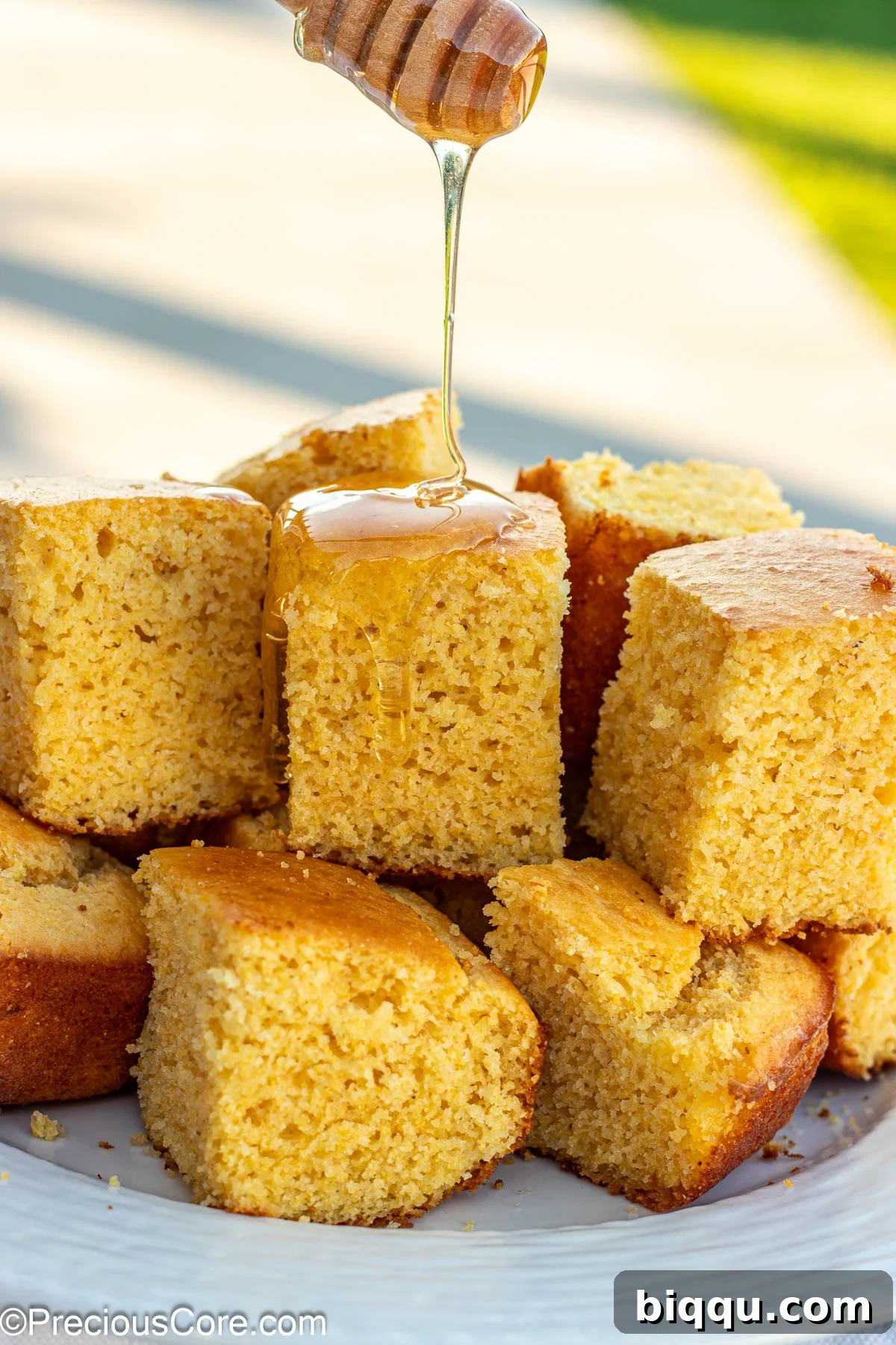 Fluffy Cornbread Without Buttermilk 2 Square slices of cornbread without buttermilk with honey drizzling on top.