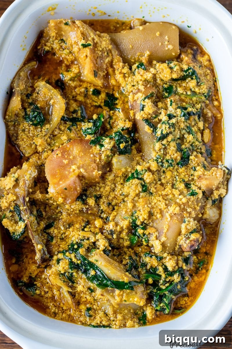 Close-up shot of steaming Egusi soup in a bowl, showing its thick texture and various ingredients.