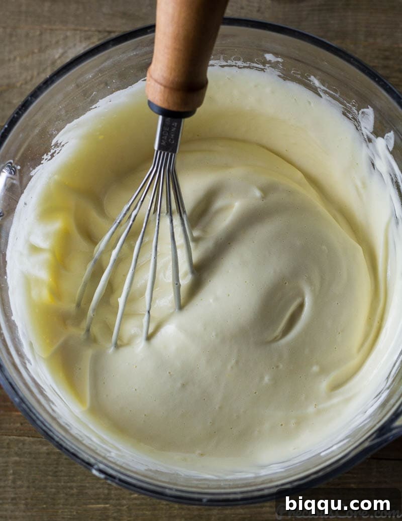 Fluffy Vanilla Sponge Cake 5 A whisk gently mixing egg whites, egg yolks, and vanilla extract in a bowl.