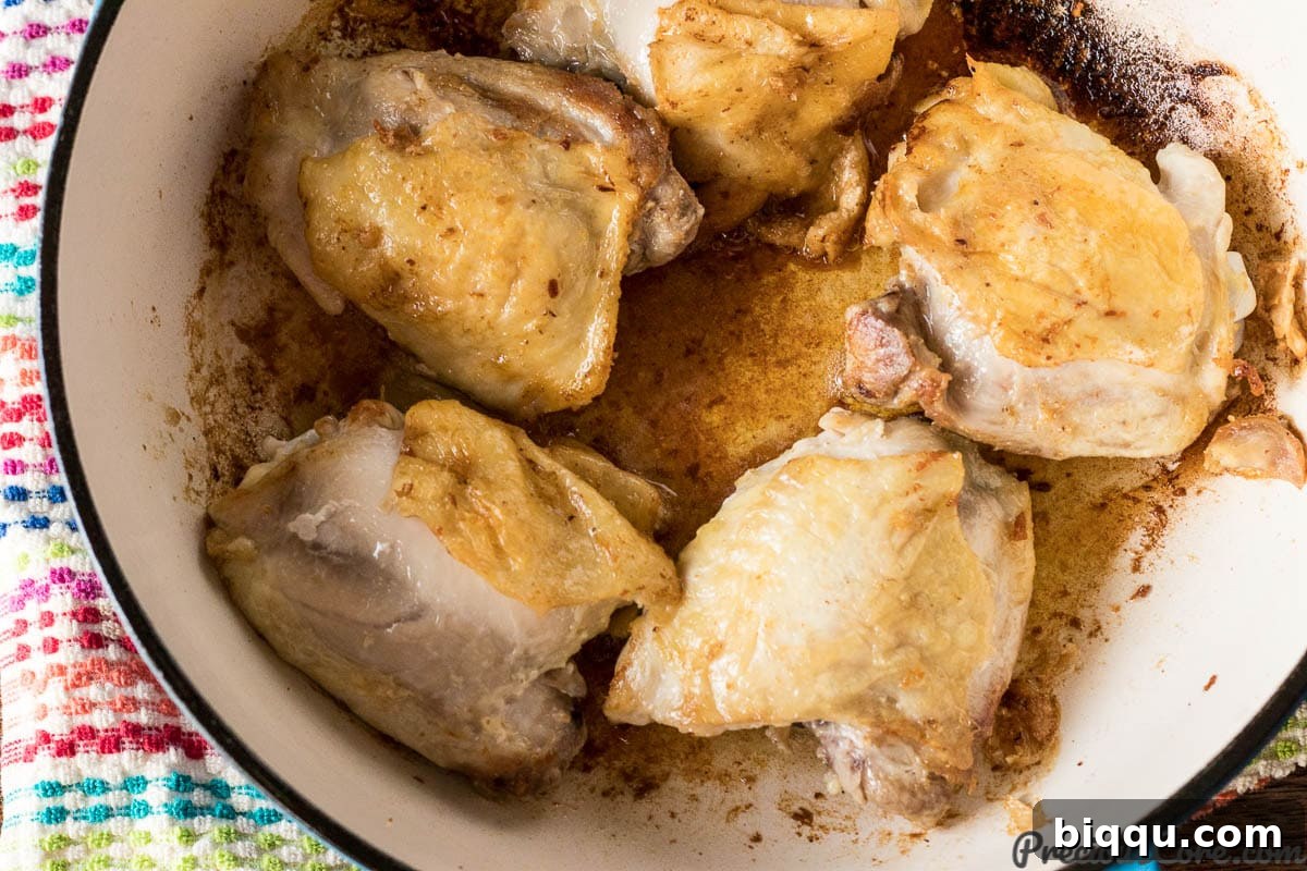 Chicken thighs searing in a hot skillet