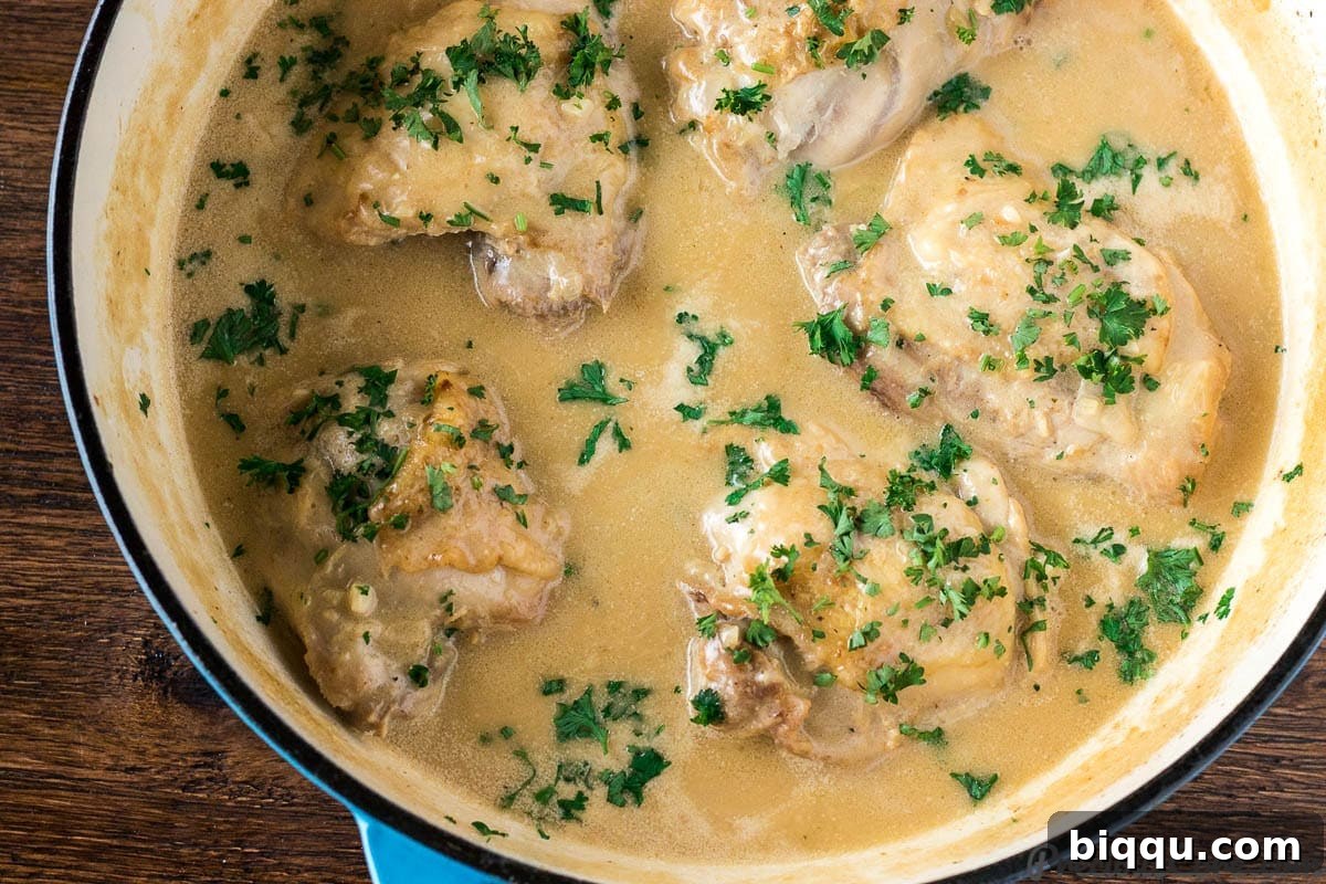 Finished Chicken in White Sauce in a skillet, garnished with parsley