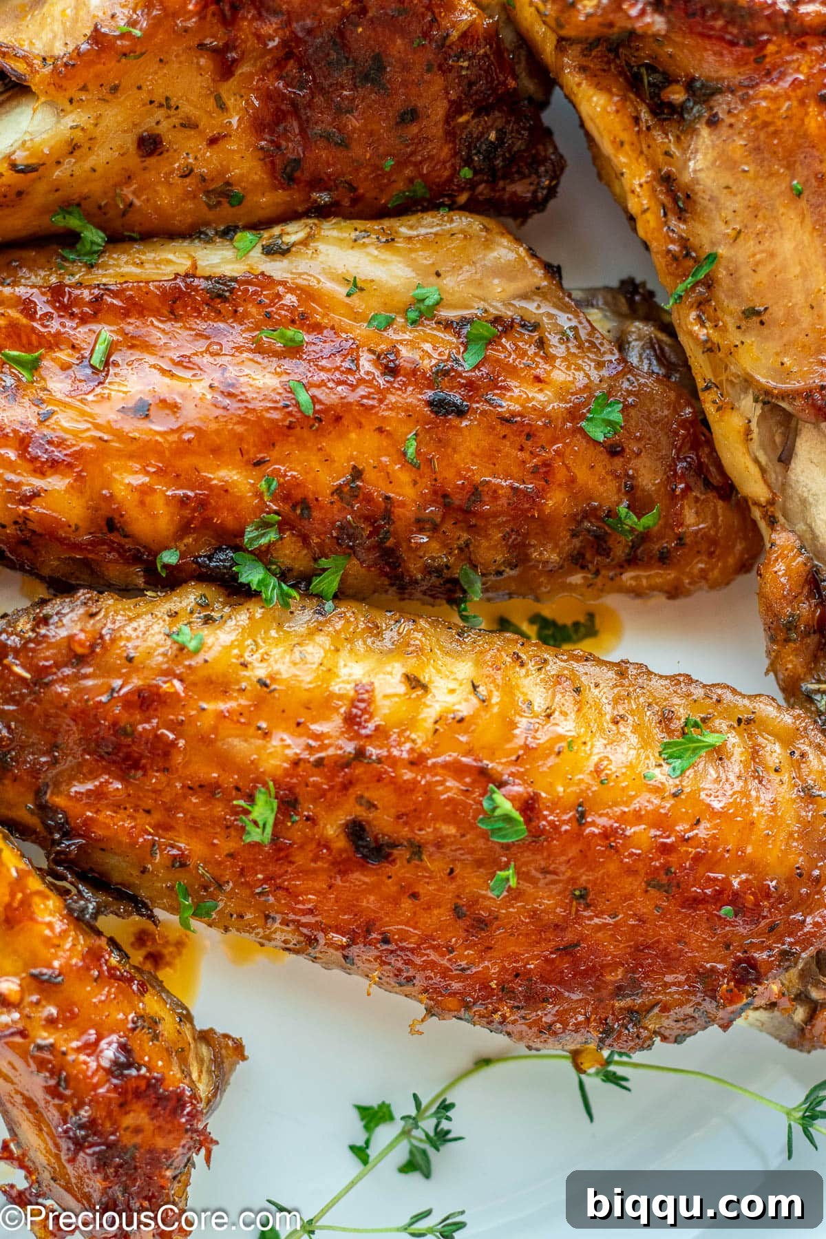 Oven Baked Turkey Wings in a white bowl, garnished with fresh herbs.