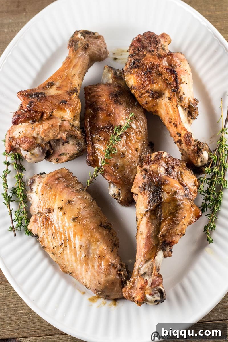 Freshly baked, golden-brown turkey wings arranged artfully on a pristine white platter.