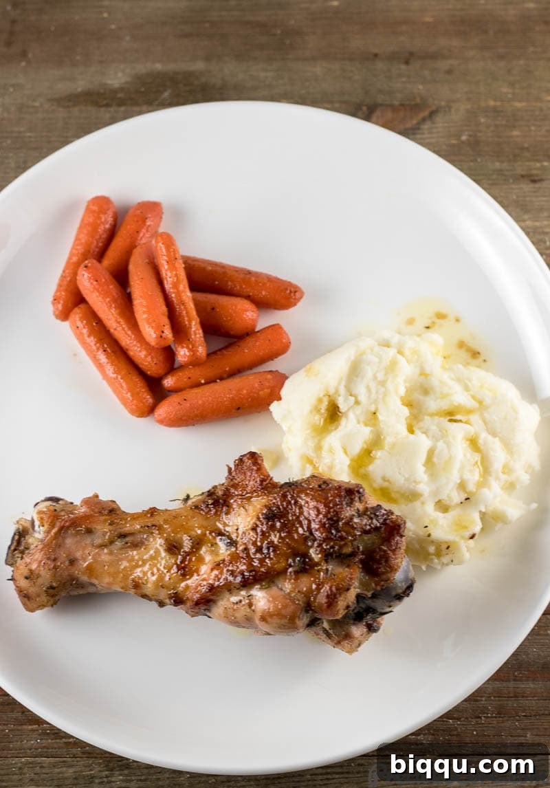 Platter of baked turkey wings served alongside creamy mashed potatoes and vibrant sautéed carrots, a comforting meal.