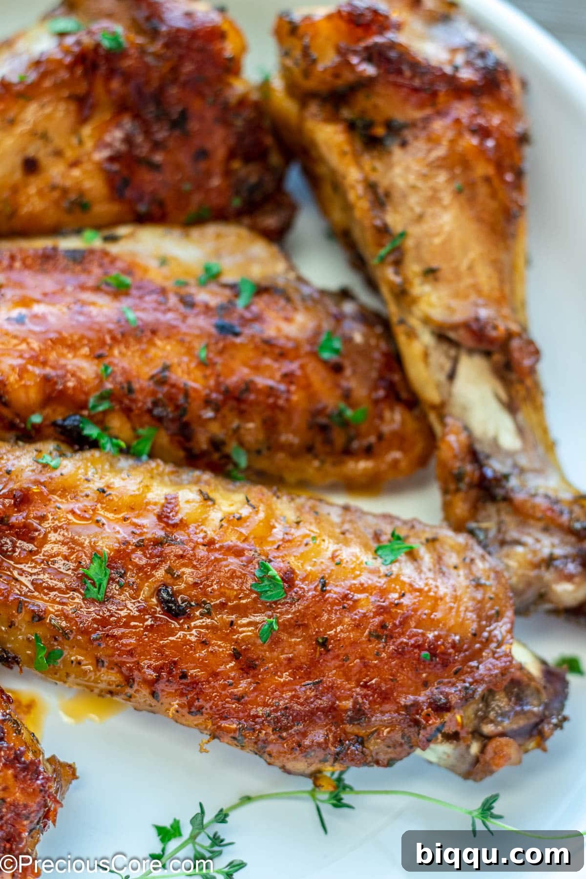 Beautifully cooked brown turkey wings garnished with a sprinkle of fresh minced parsley, enhancing their visual appeal.