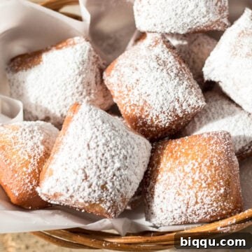 A basket filled with golden-brown beignets, dusted with powdered sugar, ready to be enjoyed.