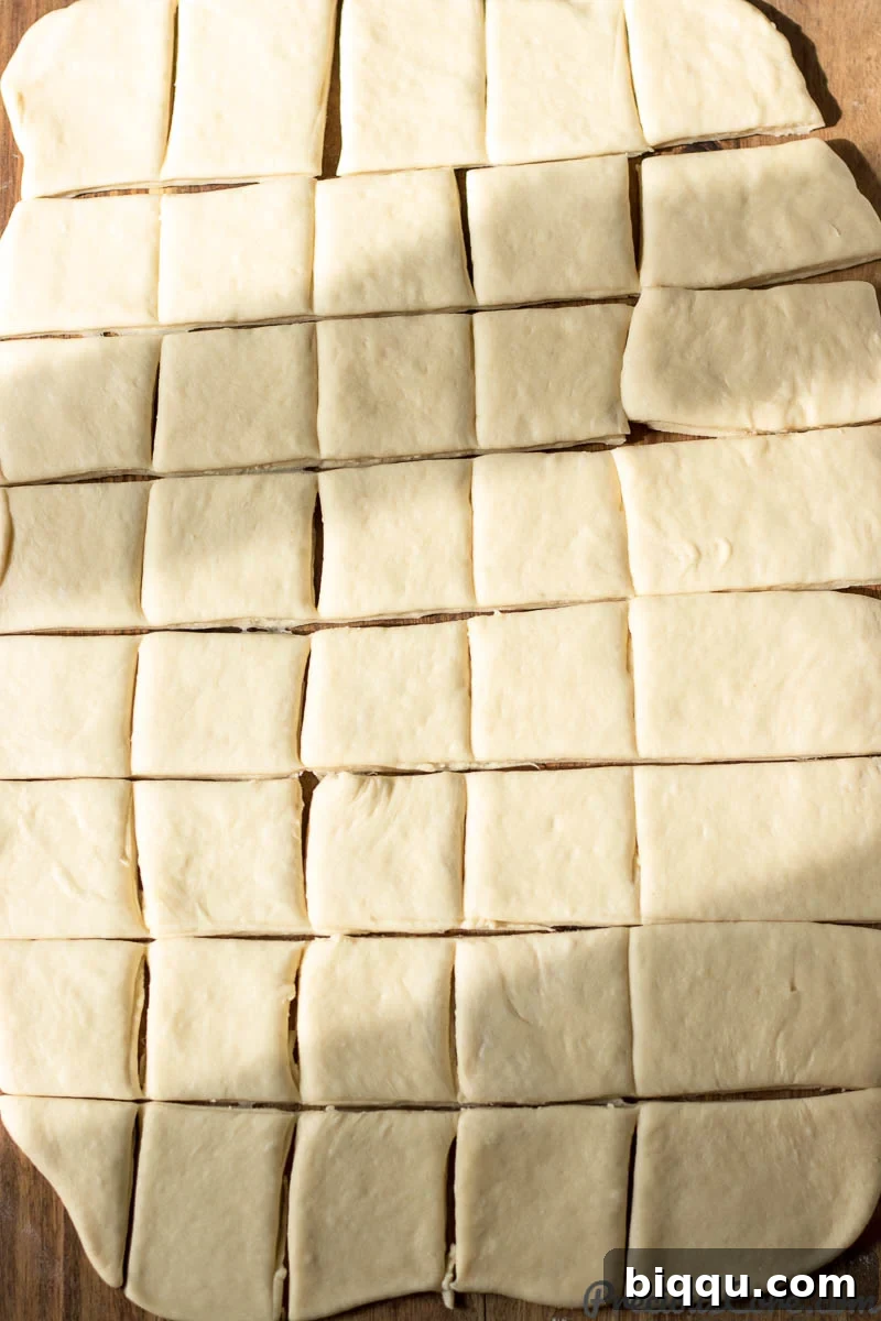 Raw beignet dough meticulously cut into uniform squares, ready for frying.