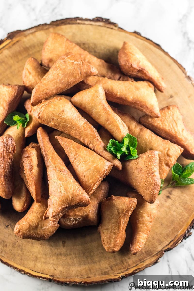 Mandazi East African Doughnuts 2 A plate piled high with golden-brown Mandazi, showcasing their perfectly fried texture.