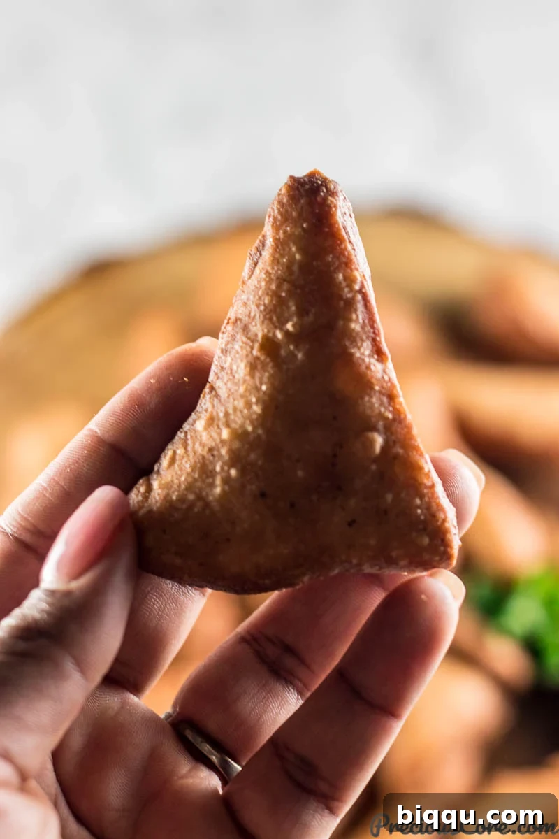 Mandazi East African Doughnuts 4 A hand holding a freshly fried, perfectly golden Mandazi doughnut.