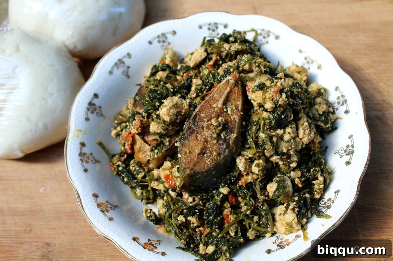 A bowl of Njama Njama with Egusi topped with fried fish.