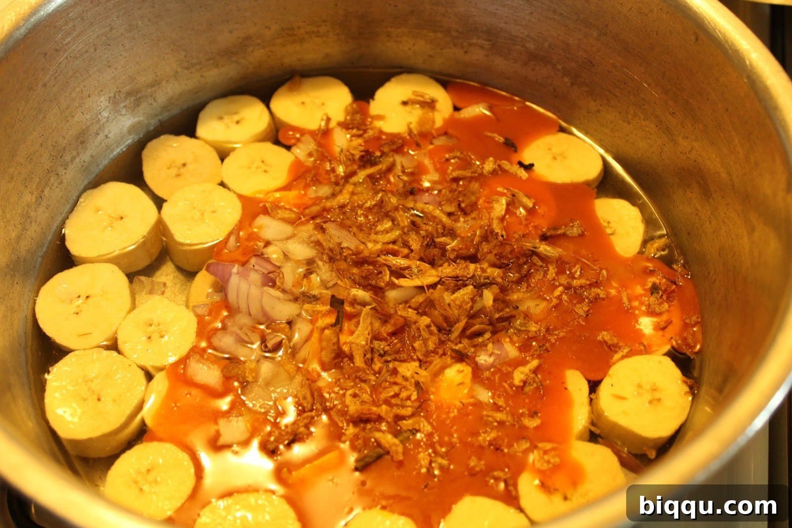 Hearty Plantain Porridge 5 Sese Plantains simmering in a pot, showing the vibrant orange colour of the palm oil blending with water and other ingredients.