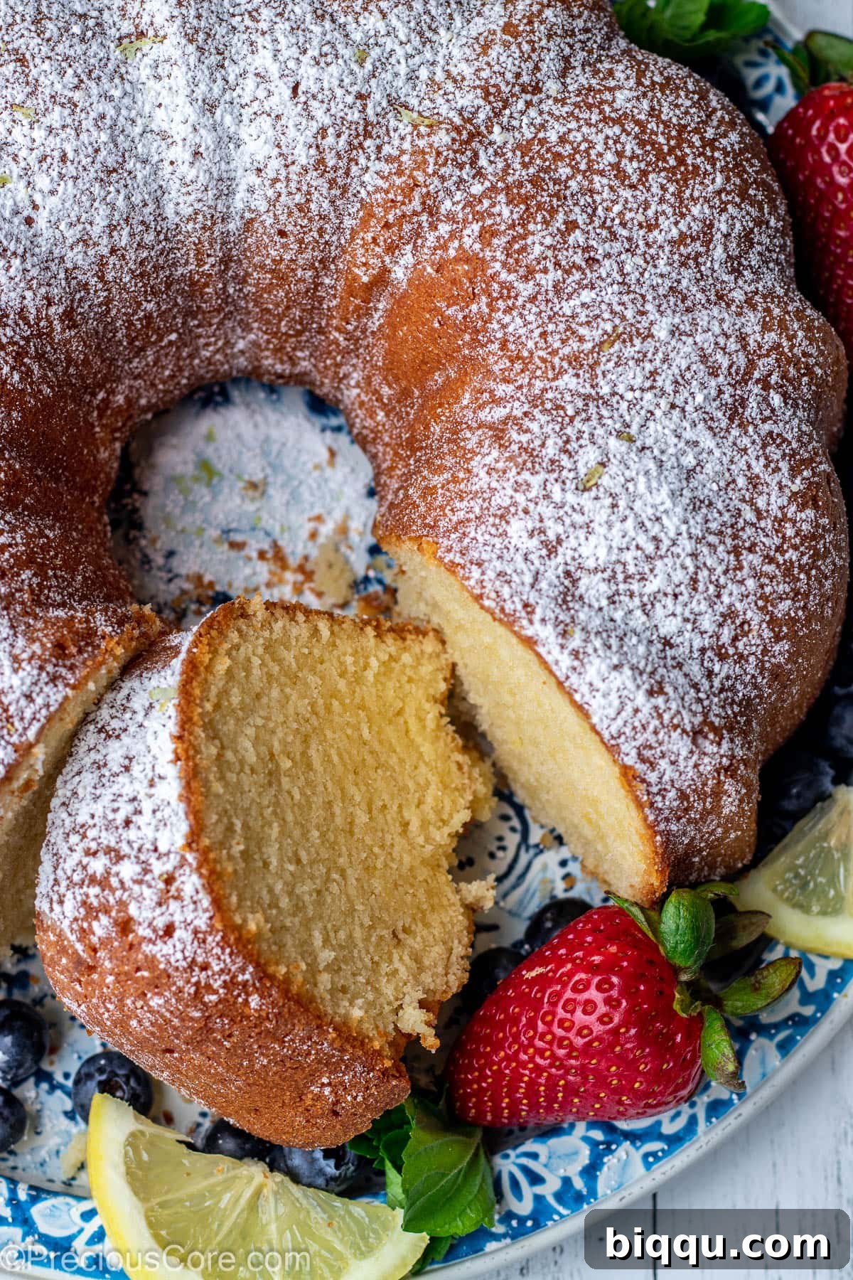 Lemon pound cake on a round platter with a piece of cake cut out.