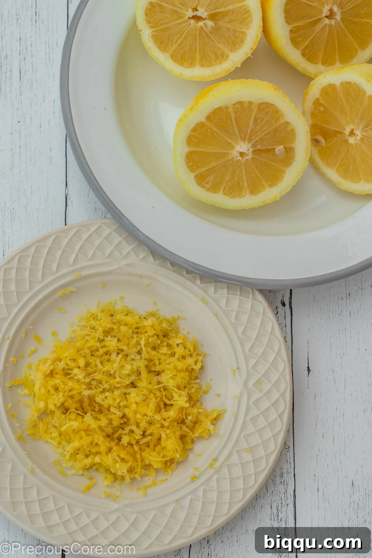 Lemon zest on one plate and lemon halves on another plate.