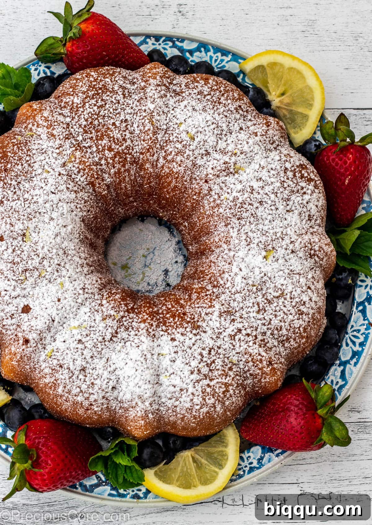 A bundt cake dusted with powdered sugar and surrounded by berries.