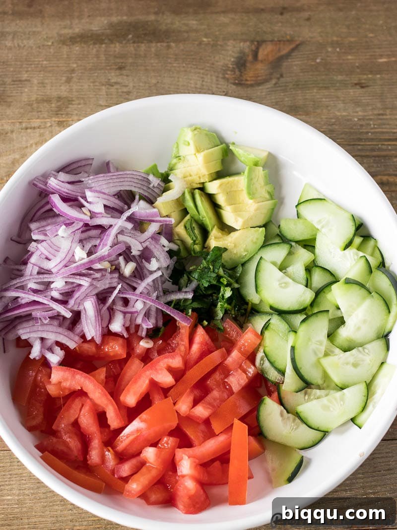 Fresh Kachumbari ingredients laid out on a plate, including tomatoes, red onions, cucumber, and avocado.