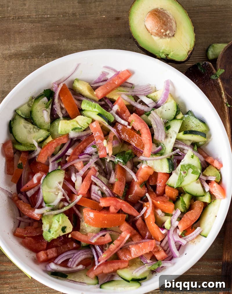 A vibrant bowl of Kachumbari salad with avocado and cucumber, showcasing fresh diced ingredients.