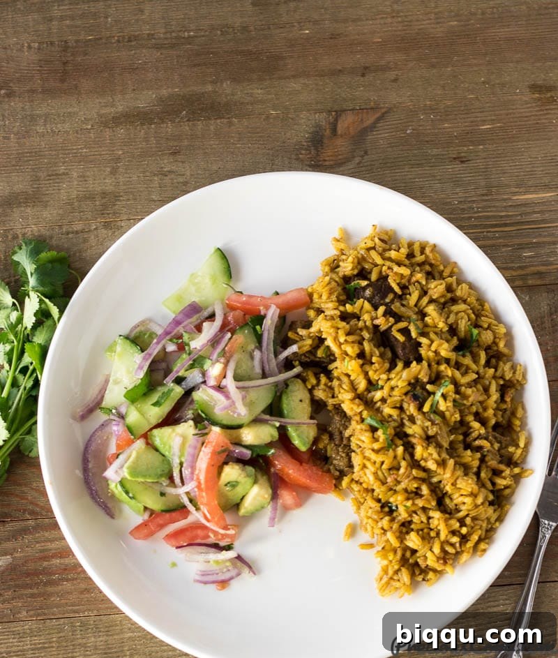 A plate featuring a serving of Pilau, an East African one-pot rice dish, accompanied by a fresh side of Kachumbari salad.