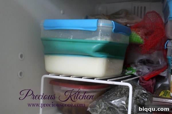 A bowl of the coconut ice cream mixture covered with plastic wrap, placed inside a freezer to begin the freezing process.