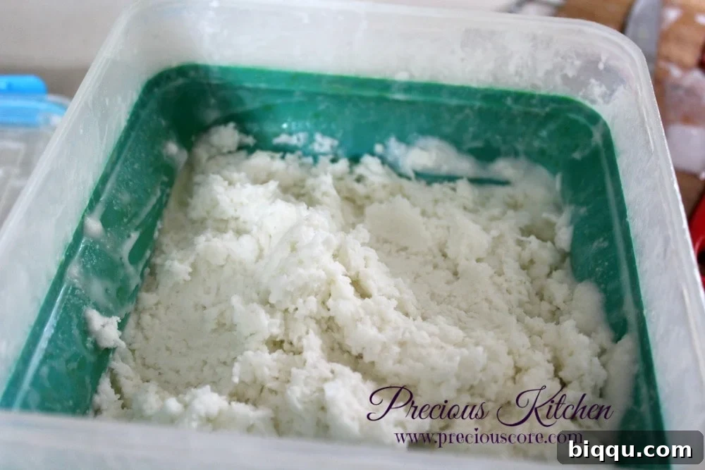 Someone beating the partially frozen coconut ice cream mixture with an electric hand mixer to improve its texture.