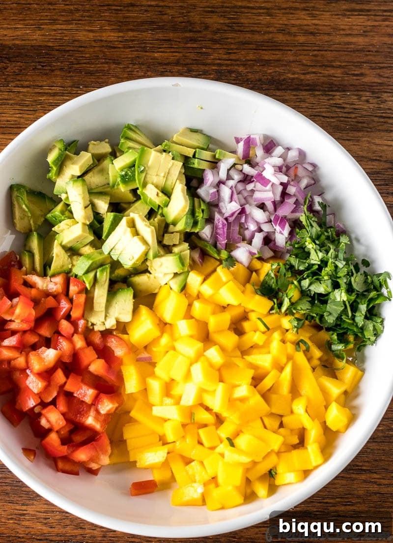 A large bowl filled with freshly chopped ingredients for Mango Avocado Salsa, ready to be mixed.
