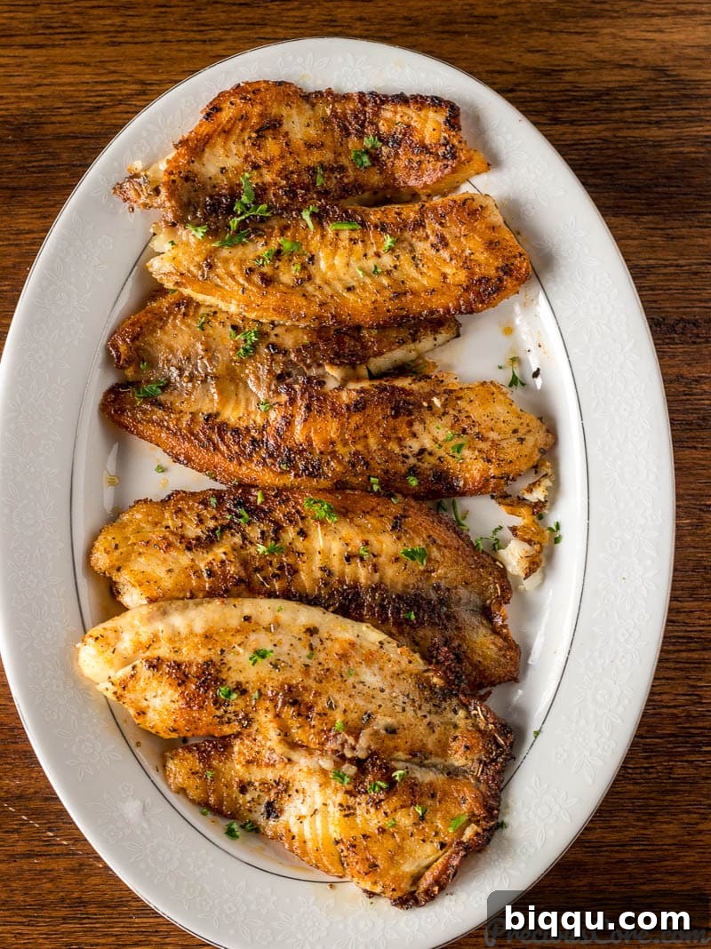 Freshly pan-seared tilapia fillets arranged neatly on a serving tray after cooking.