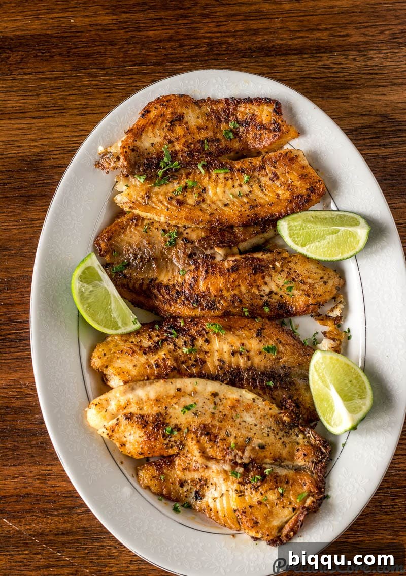 Pan Seared Tilapia presented on a elegant serving tray, garnished with fresh lime wedges.