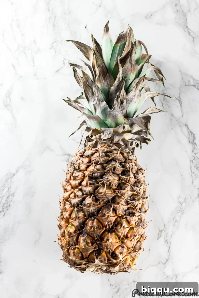 A perfectly ripe fresh pineapple resting on an elegant marble countertop, ready to be sliced for the cake, highlighting its golden skin and vibrant crown.