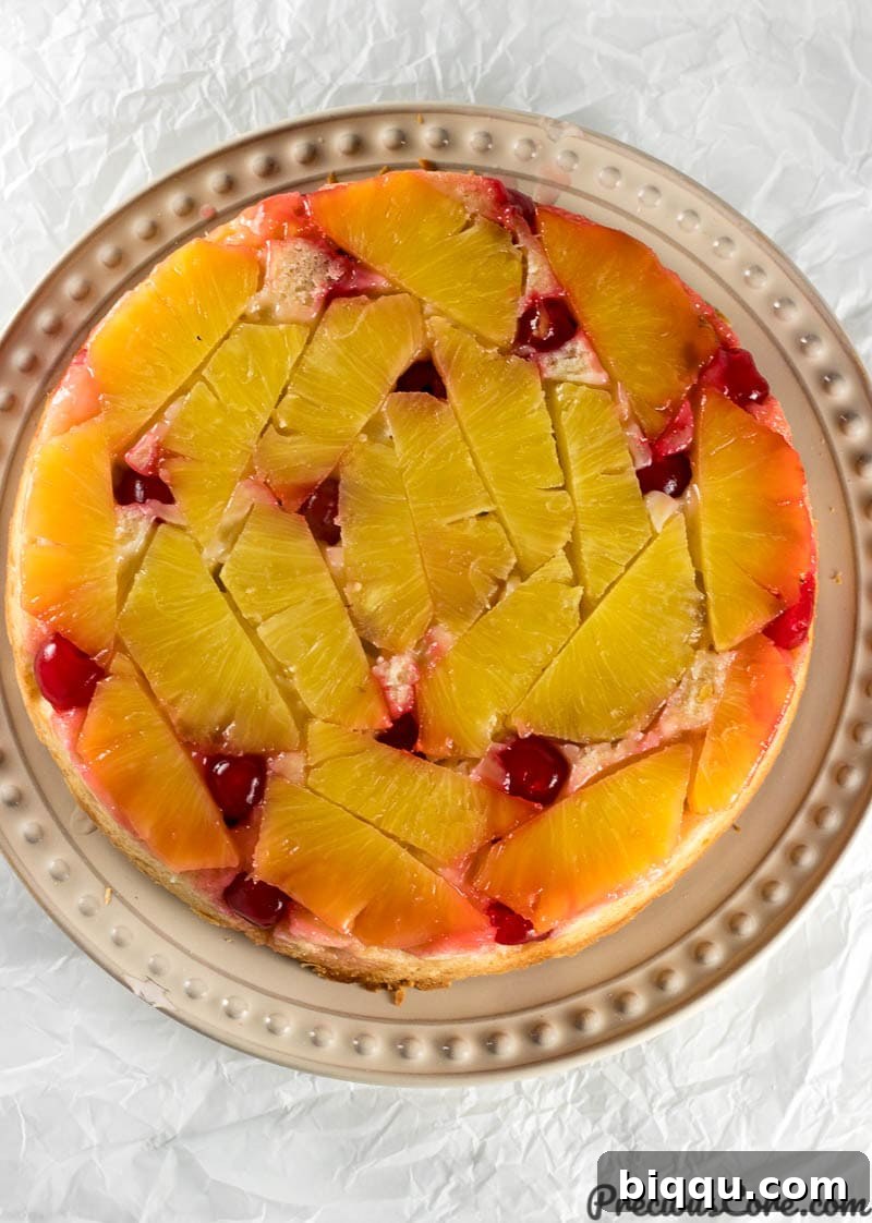 The stunning Pineapple Upside Down Cake, freshly inverted onto a serving plate, showcasing its beautiful caramelized fruit topping and golden crust.