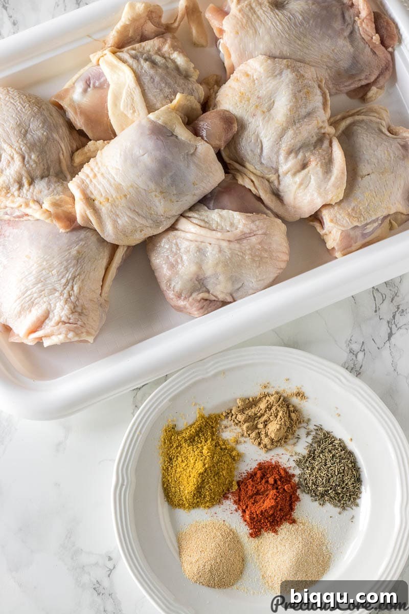 Dry rub ingredients on a plate and raw chicken thighs on a tray