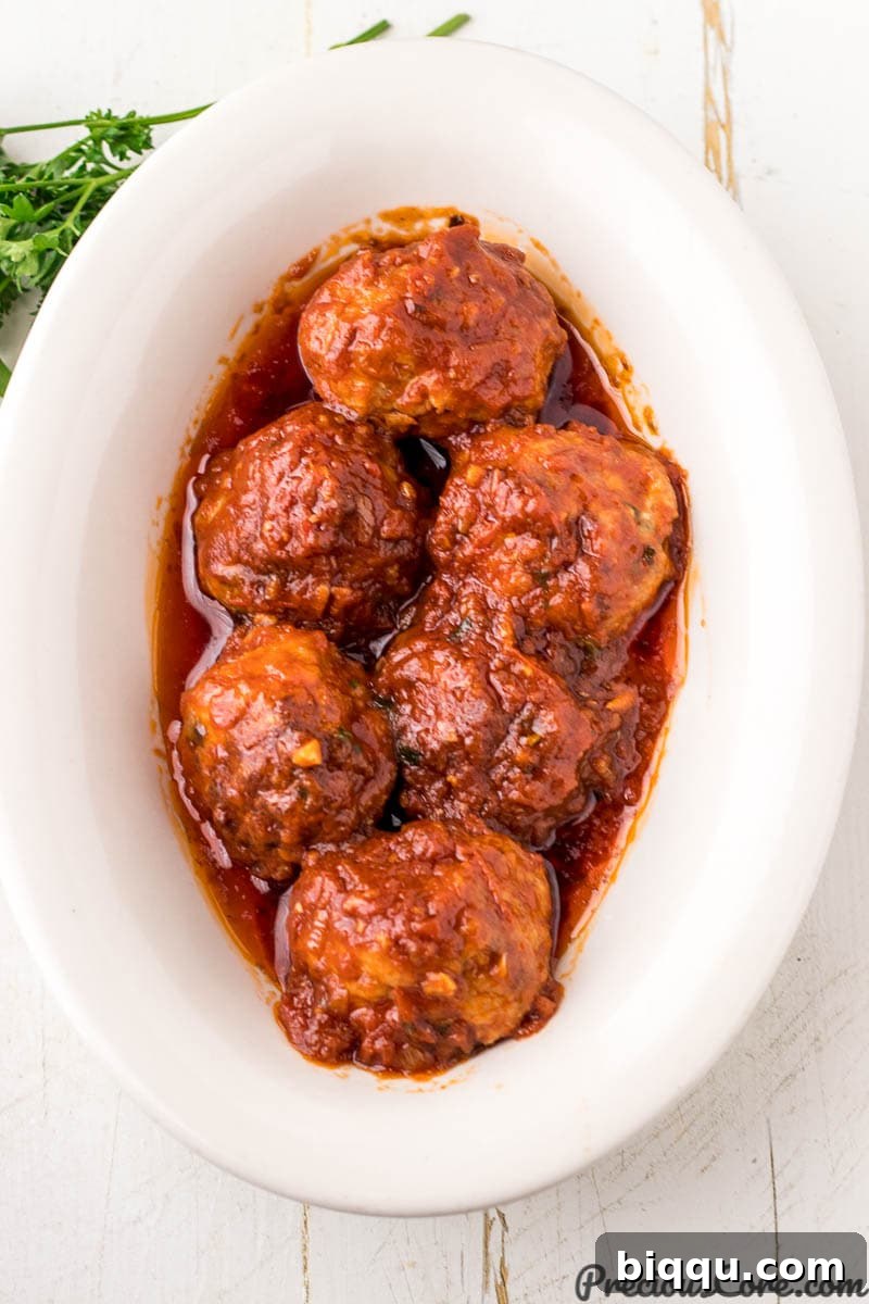 A serving bowl filled with savory chicken meatballs in rich tomato sauce, ready to be paired with spaghetti.