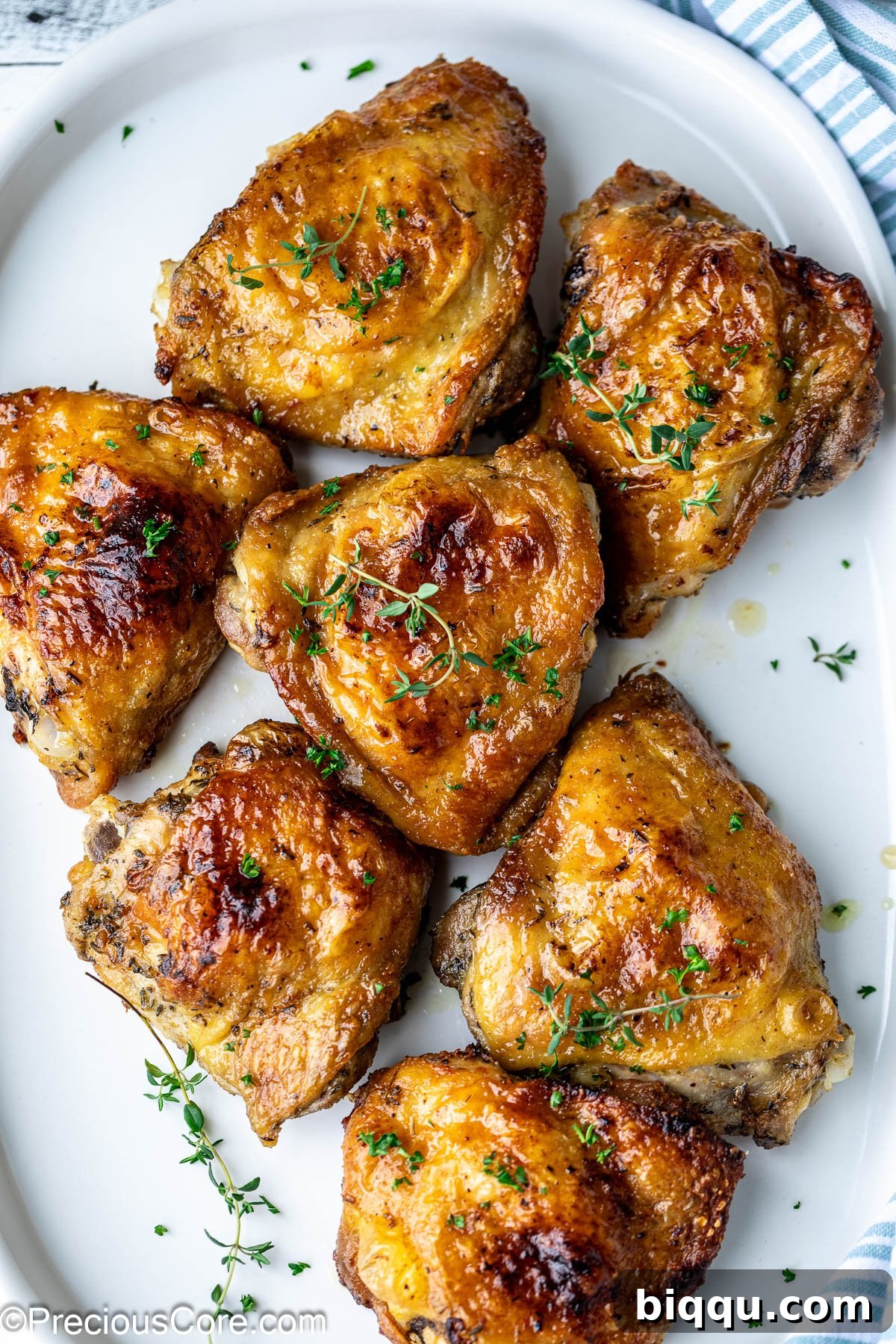 Mayonnaise chicken thighs garnished with fresh thyme on a pristine white platter, ready to be served.