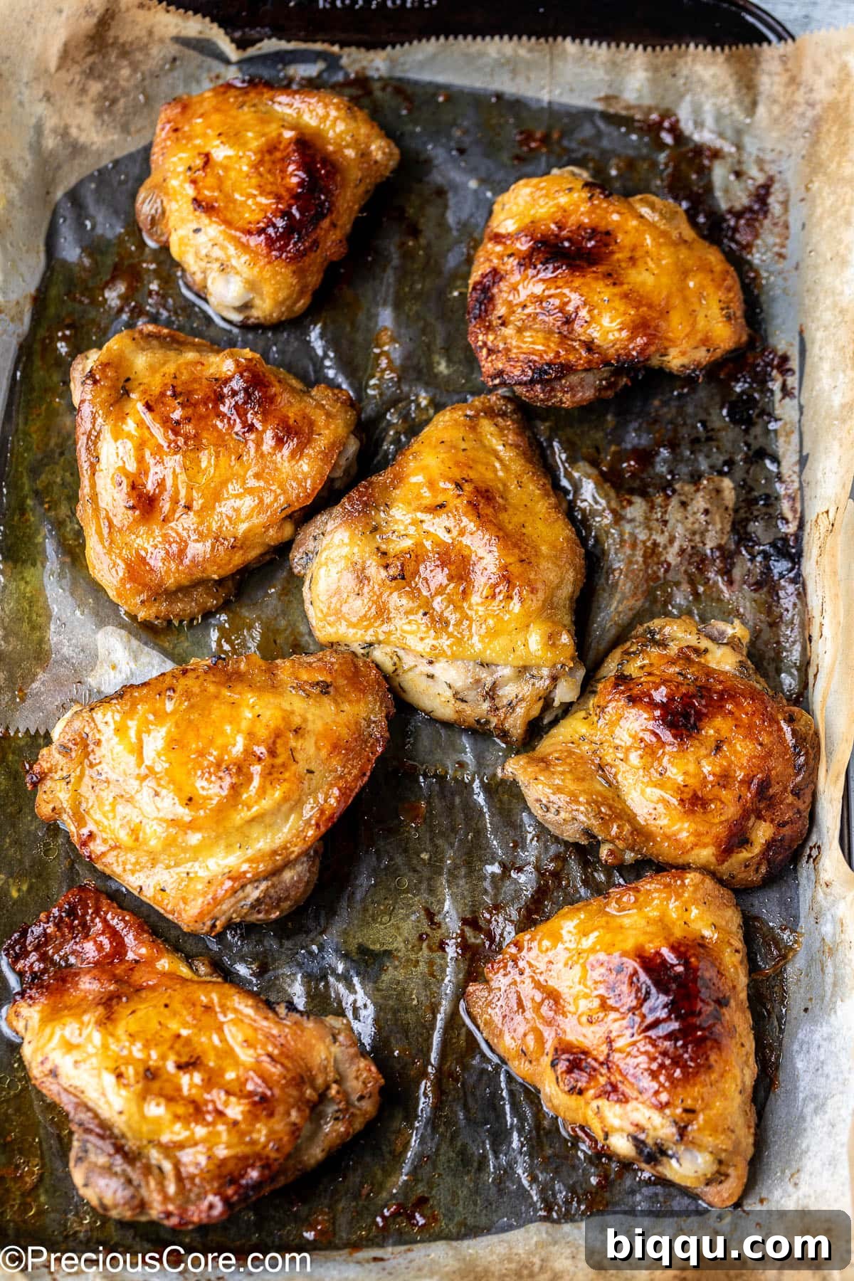 Perfectly broiled mayonnaise chicken thighs, golden brown and glistening, arranged neatly on a baking sheet lined with parchment paper.